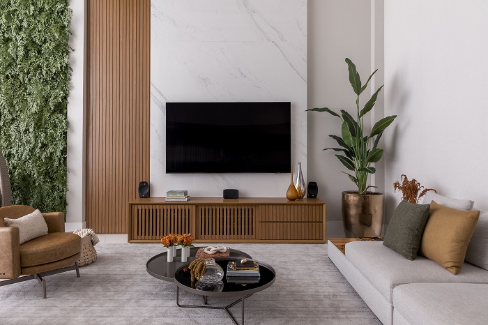 TV ganha painel de porcelanato ao longo de pé direito duplo em apartamento de 240 m²