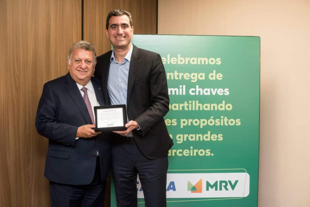 Carlos Vieira, presidente da Caixa Econômica Federal (CEF) e Eduardo Fischer, CEO da MRV&CO seguram uma placa de homenagem