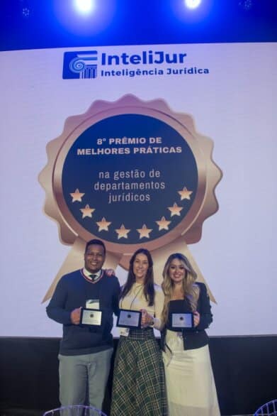 um home e duas mulheres segurando uma placa de reconhecimento por um premio recebido na área jurídica