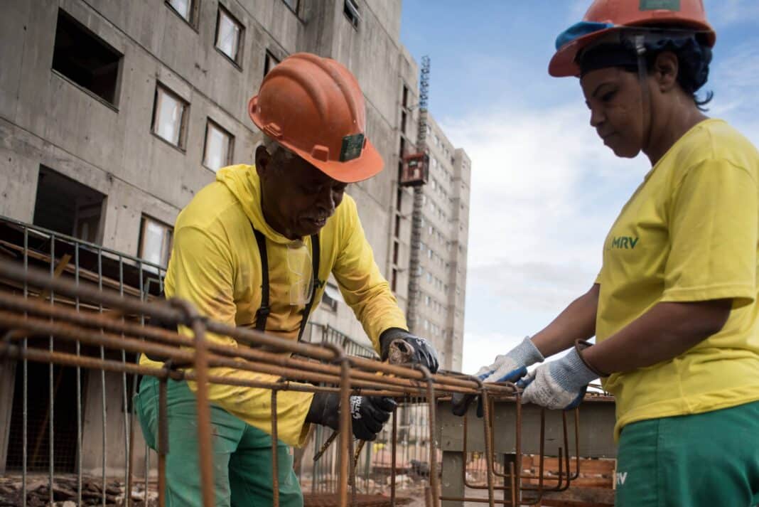 homem e mulher trabalhando na construção civil na amarração de barras de ferro